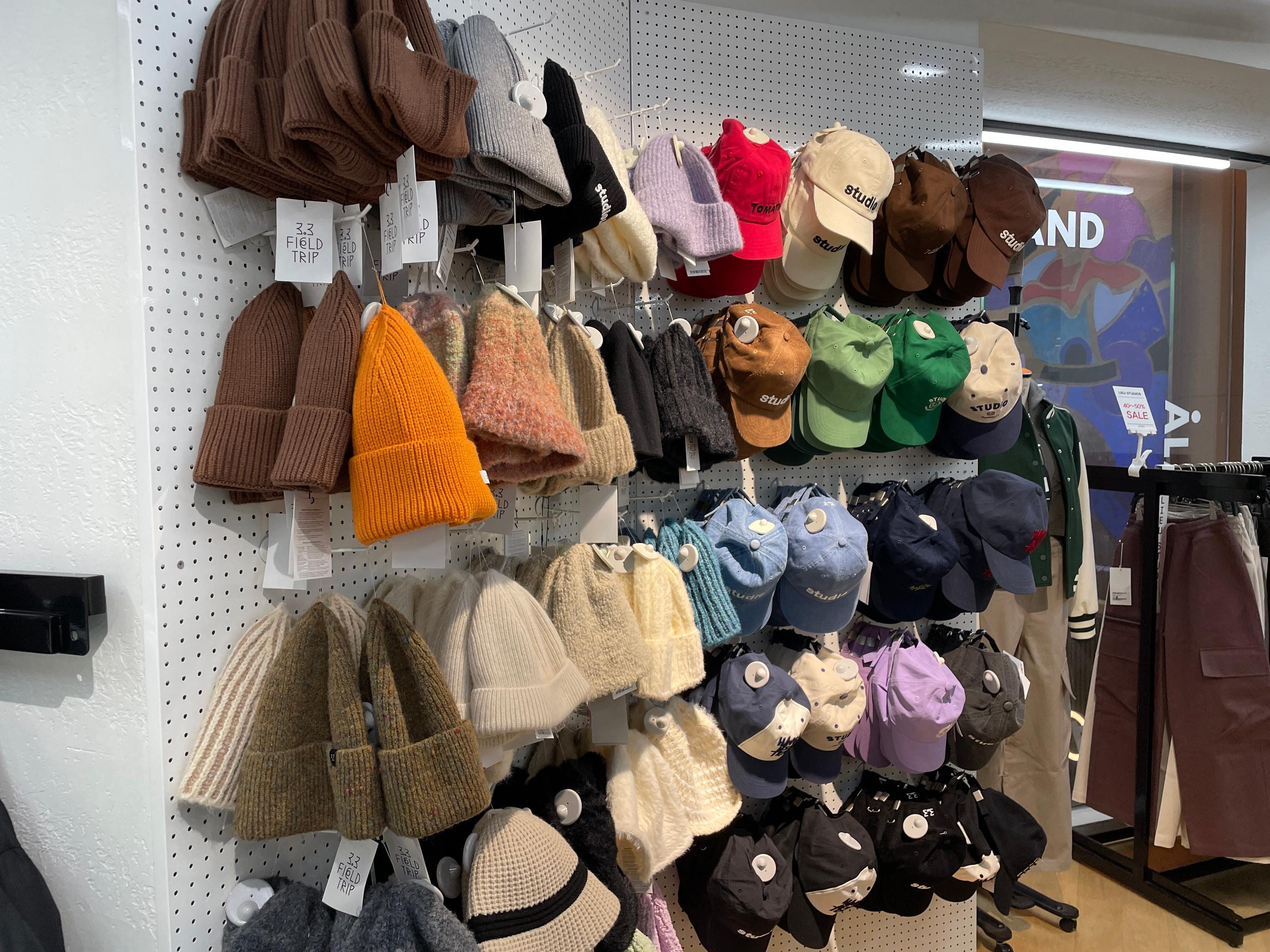 ALANDの店舗内にディスプレイされた、色とりどりのキャップとビーニーが整然と並ぶショッピングラックです。