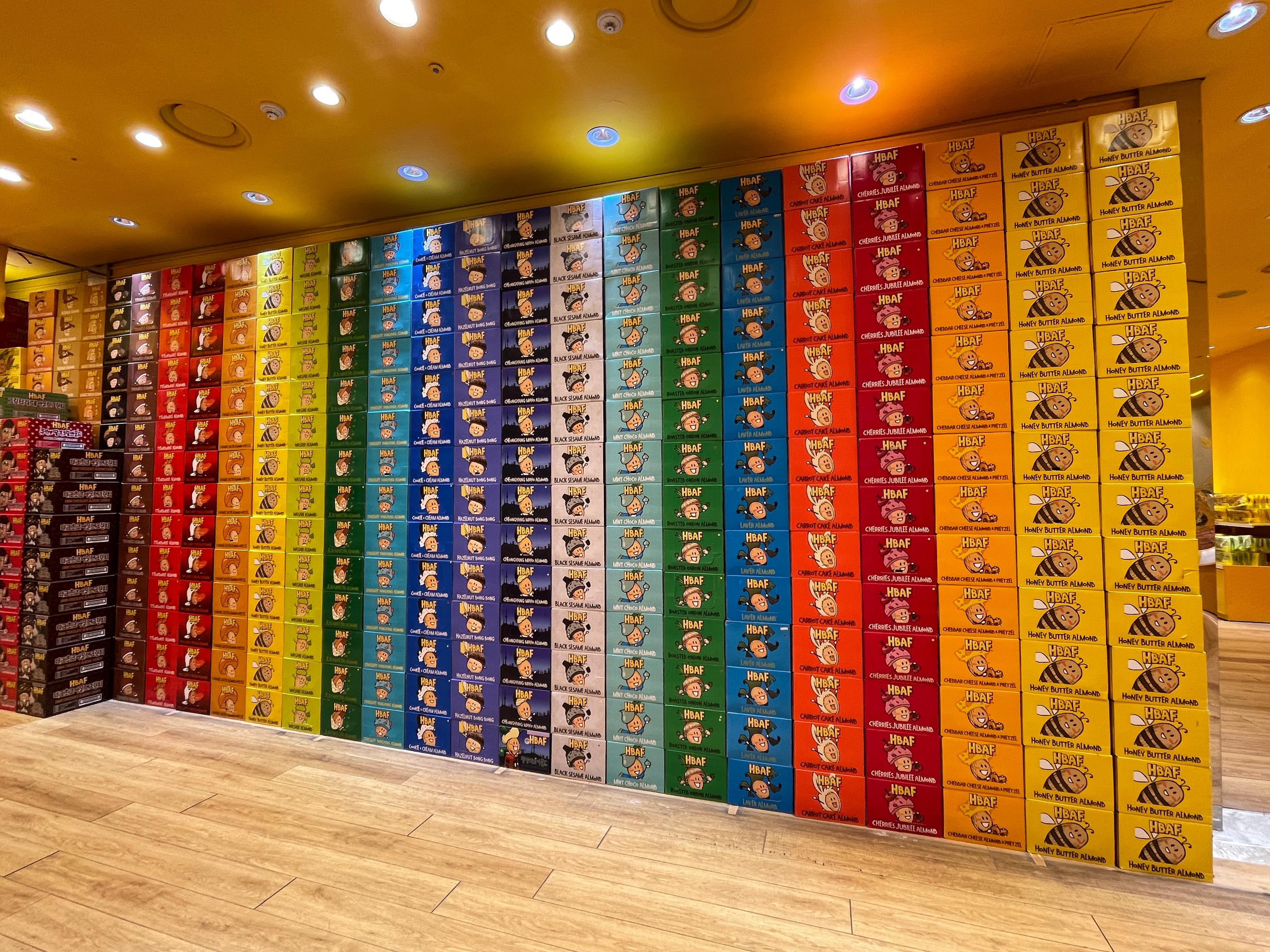 多彩なカラーパッケージに包まれた、HBAFの様々なフレーバーのアーモンドが陳列された棚の韓国HBAFアーモンドストアの内部風景です。