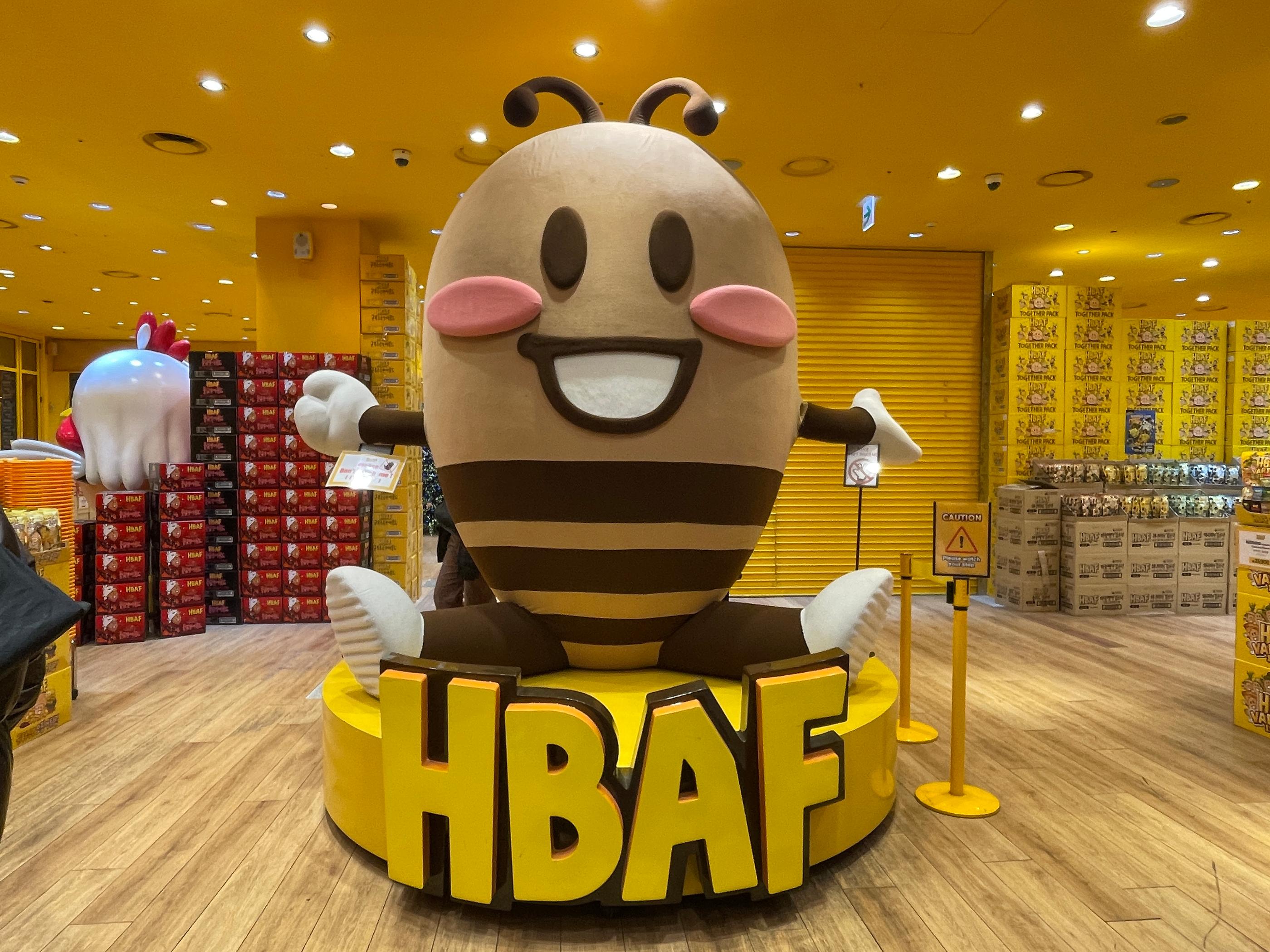 HBAFの巨大なマスコットキャラクターが店内に置かれている、明るい黄色のテーマでデザインされた韓国のHBAFアーモンドストアの内部風景です。