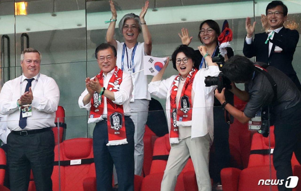 韩国足球比赛中，观众在看台上为球队加油，戴着红色围巾和韩国国旗的热情支持.