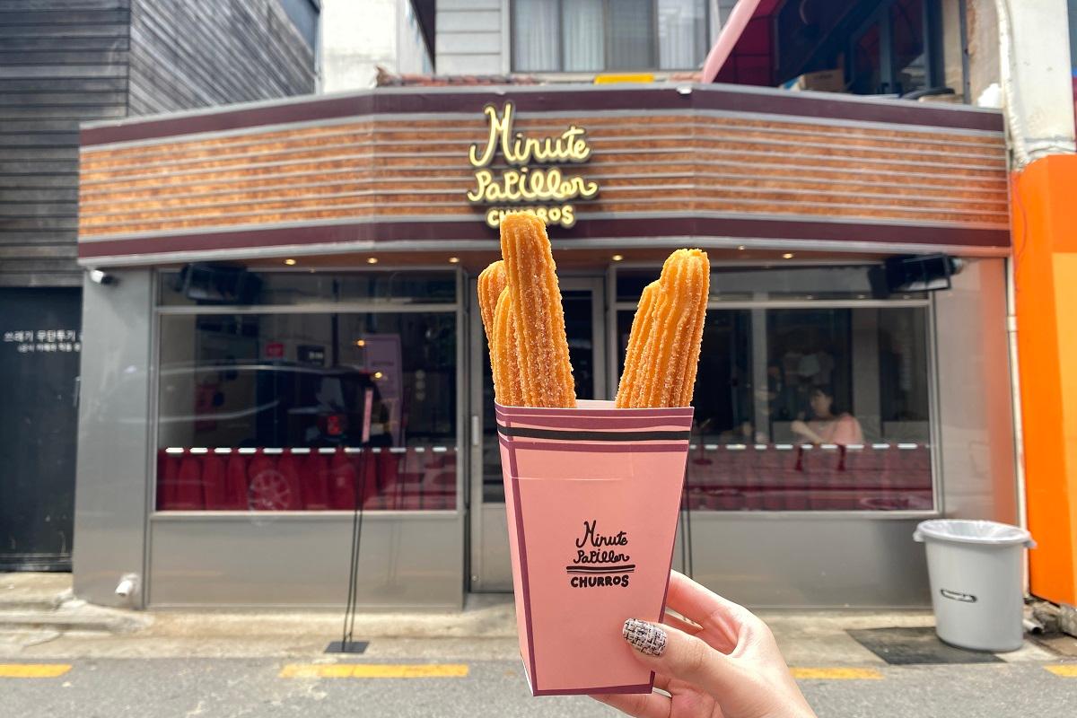 Minute Papillon 狎鴎亭ロデオで行列ができる人気のチュロス店。チョコソースと一緒に楽しむ手元のチュロスが魅力の一枚です。