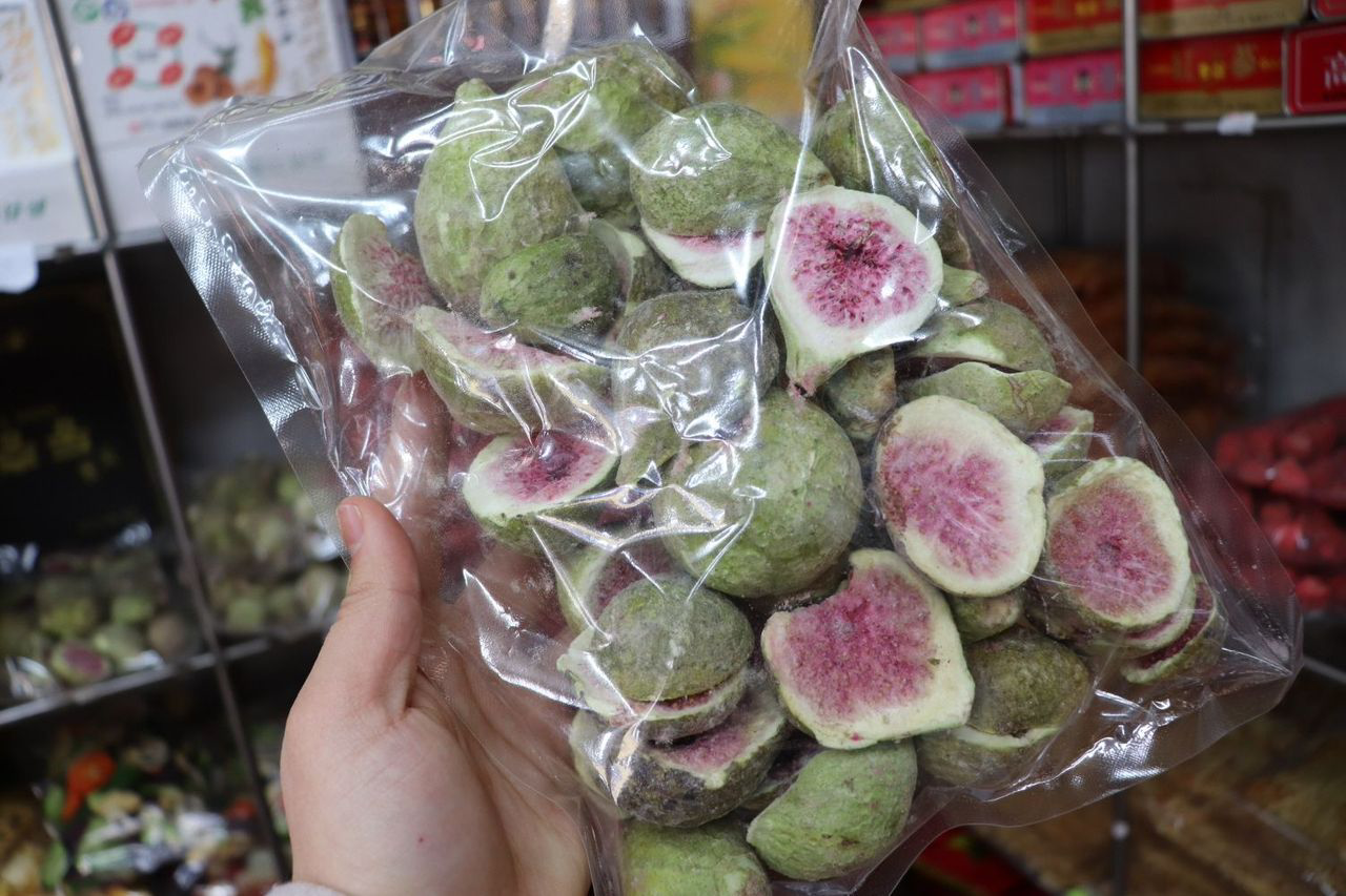 A hand holding a bag of cut green figs from Jangan Store at Namdaemun Market.
