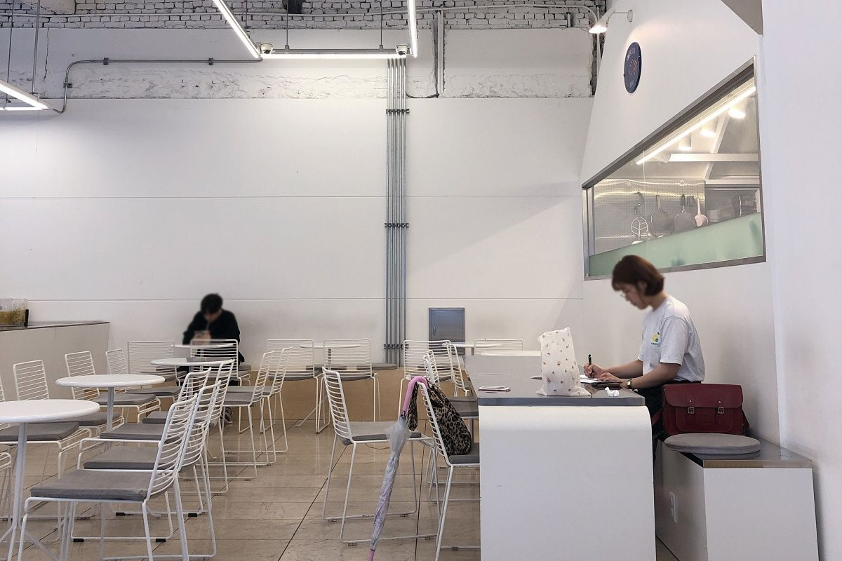 Luft Coffee 咖啡廳內部裝潢，設計簡約，白色桌椅搭配，透入柔和的自然光。