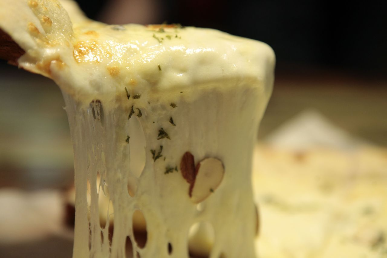 Strings of melted cheese on Gorgonzola pizza at Hwa Tteok, reflecting a perfect combination of soft dough and savory toppings.