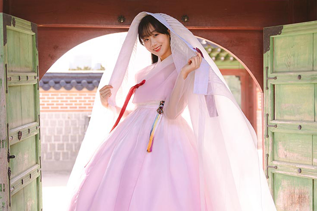 穿著粉紅婚禮韓服的女子，在傳統韓式大門下展示婚禮的傳統儀式