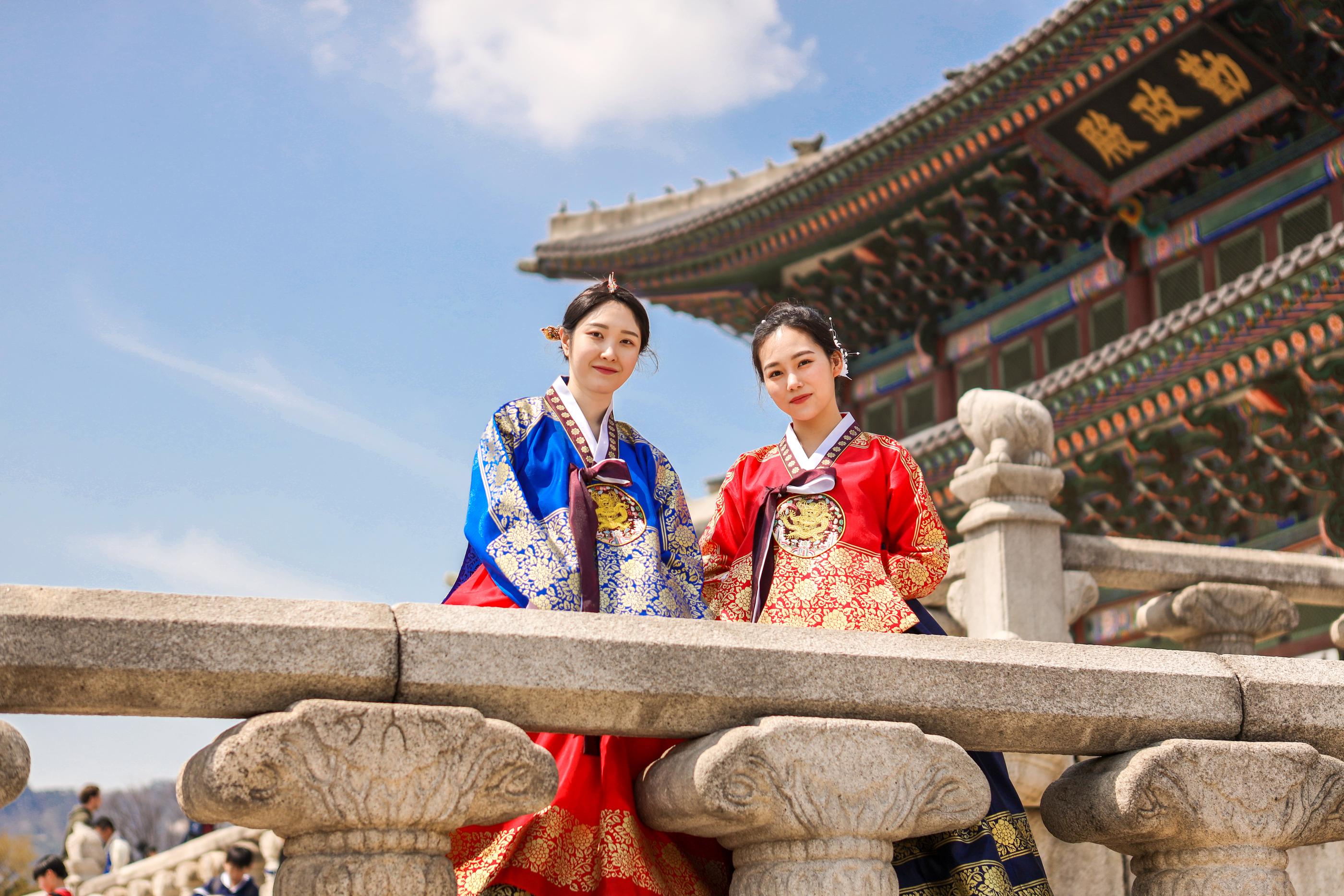 テーマ韓服を着た二人が壮麗な宮殿と青空を背景にした景色