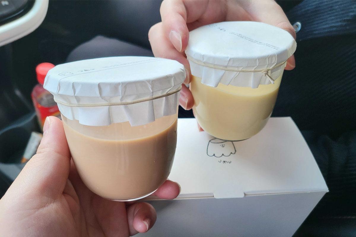 People holding two Umu puddings.