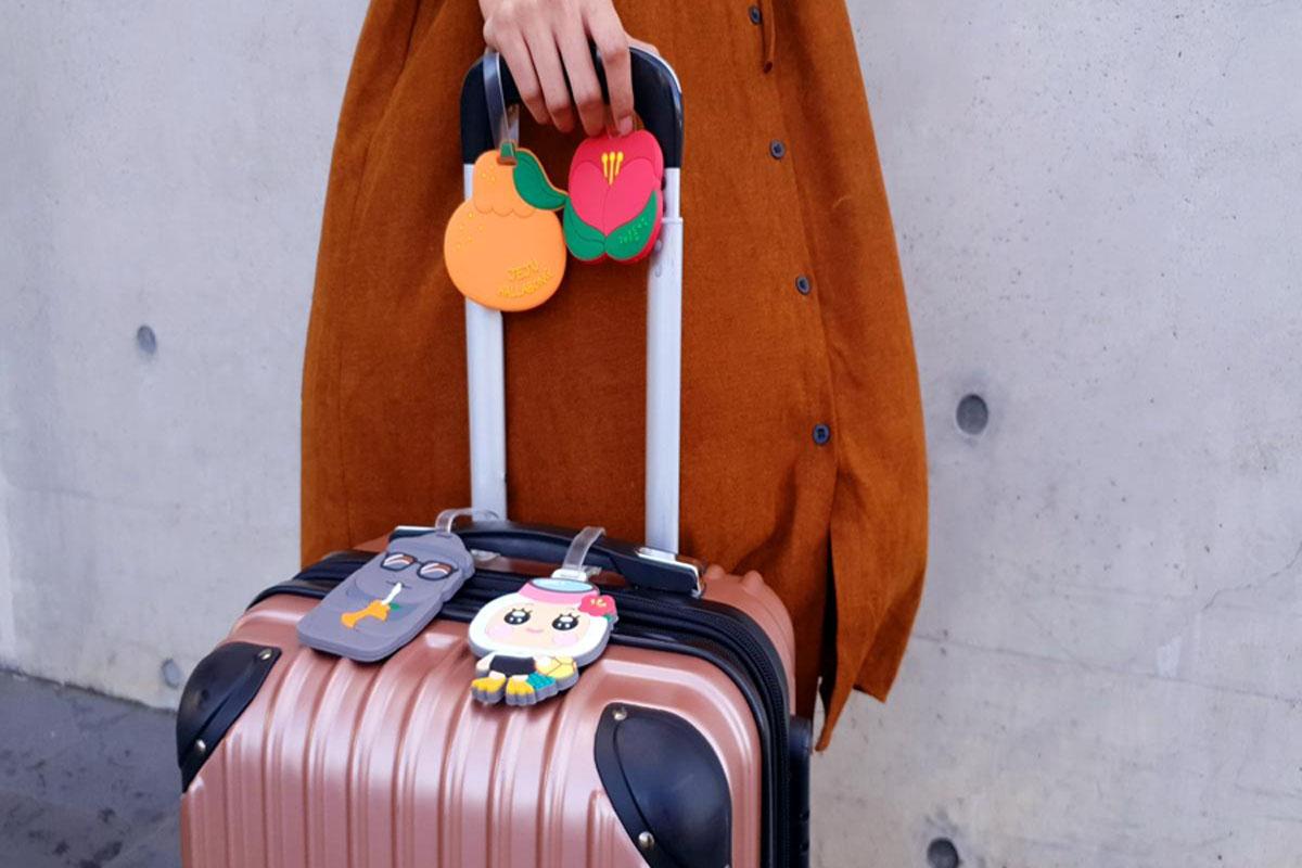 A girl pulling a suitcase decorated with Jeju name tag
