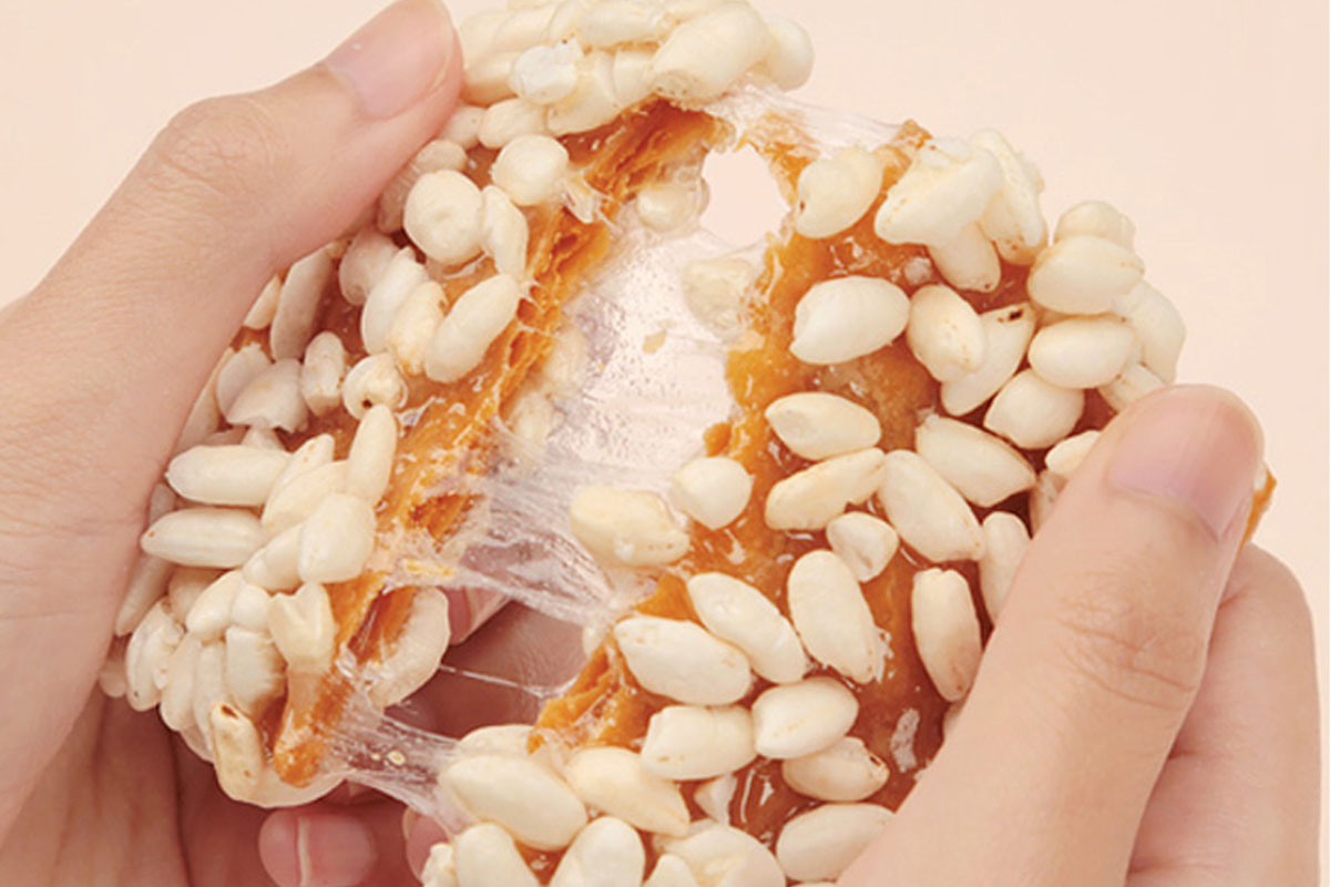 A person breaking a tangerine flavored cookie in their hands.
