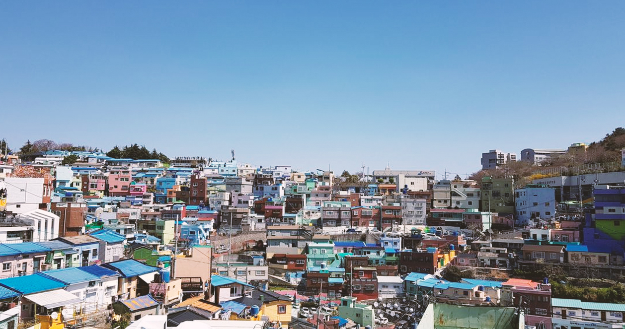 甘川文化村的全景，藍天背景下的村莊建築層疊有致，讓人感受到獨特的韓國風情。