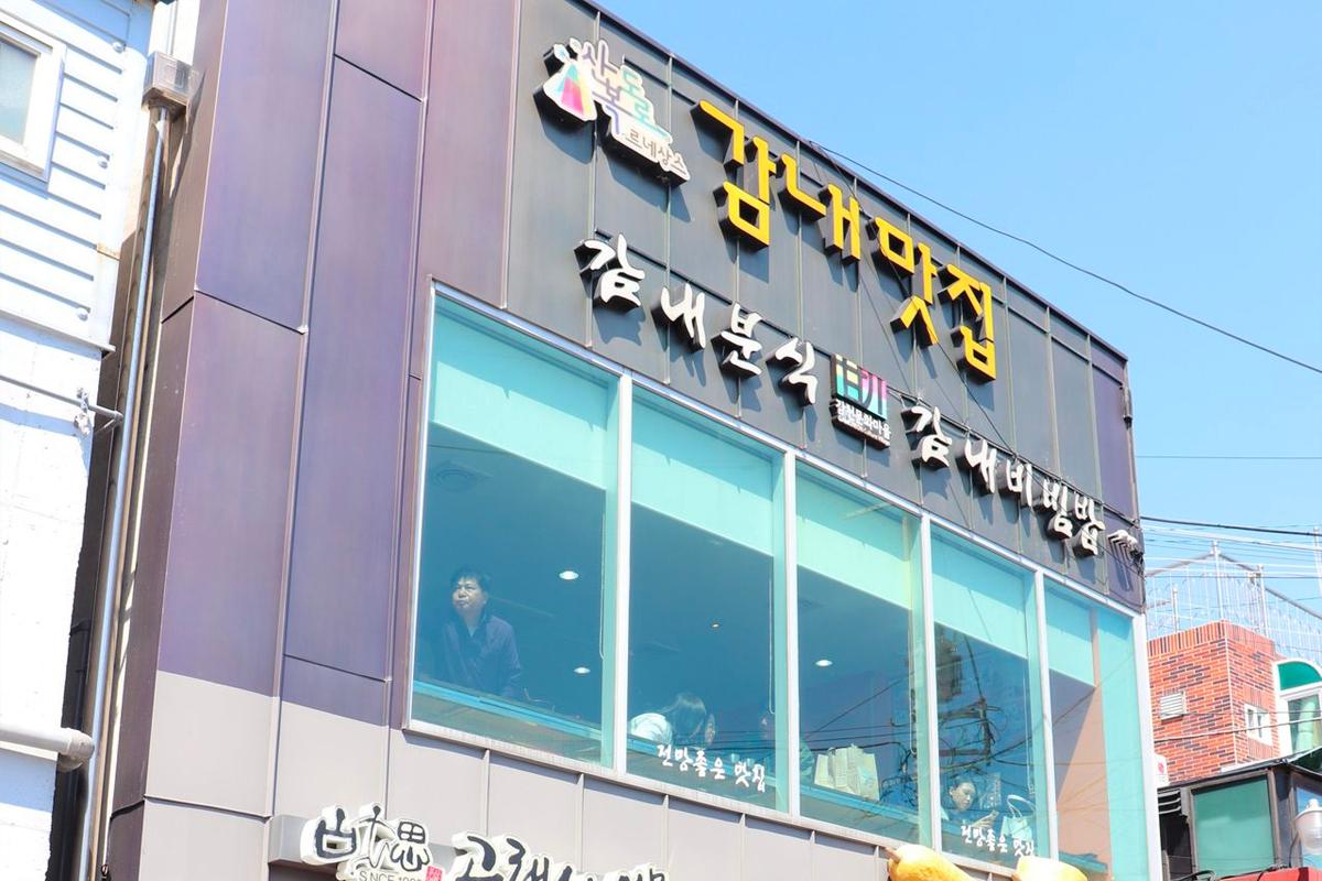 甘內拌飯店鋪外的標誌顯示著豐富的韓式套餐，透明玻璃窗透出餐廳內部的一瞥。