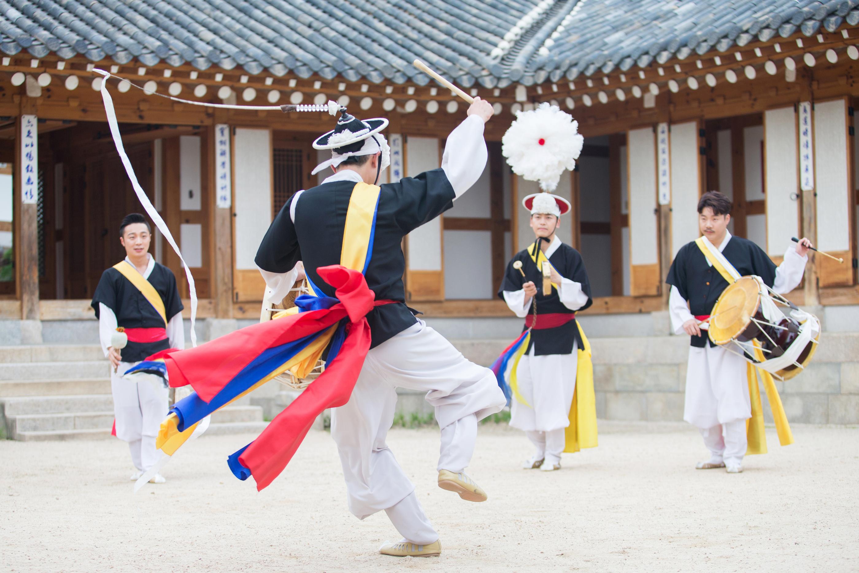 Traditional Korean folk dance performance with musicians playing instruments in vibrant costumes.