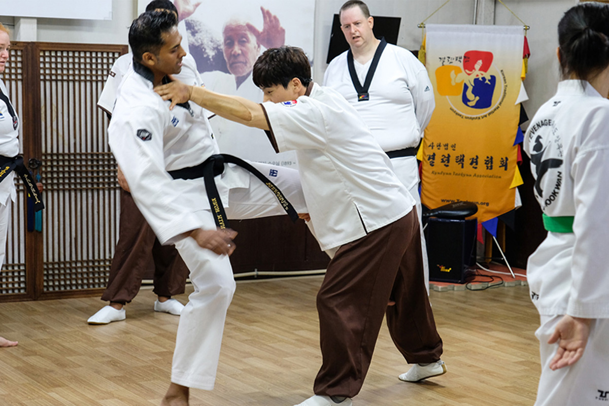Taekwondo training session in Seoul showing a group engaging in hand-to-hand combat techniques.