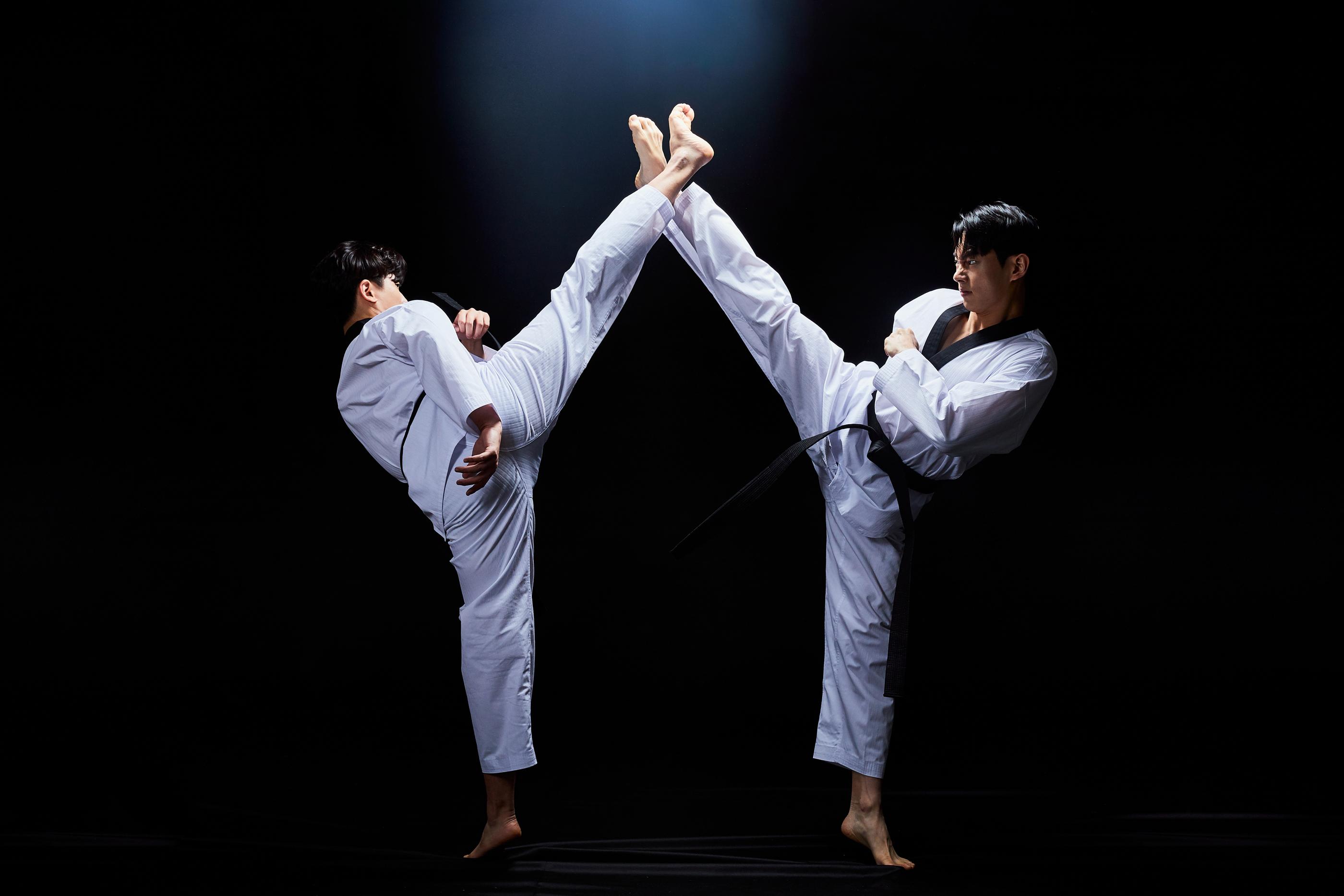 Two taekwondo practitioners performing high kicks as part of a demonstration in Seoul.