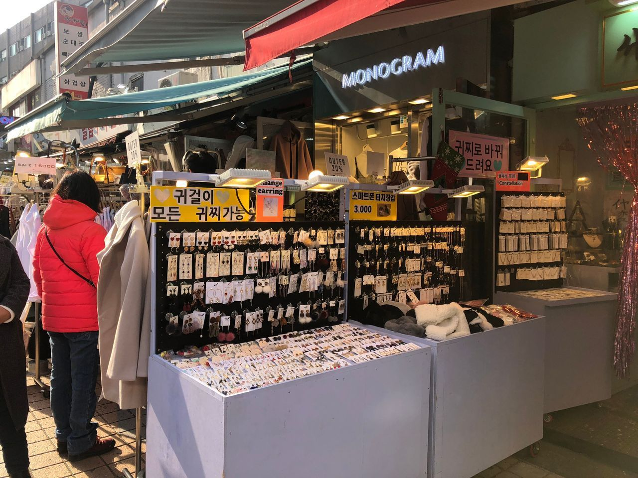 Bancarella di accessori e orecchini a Hongdae con segnaletica per varie marche a prezzi convenienti.