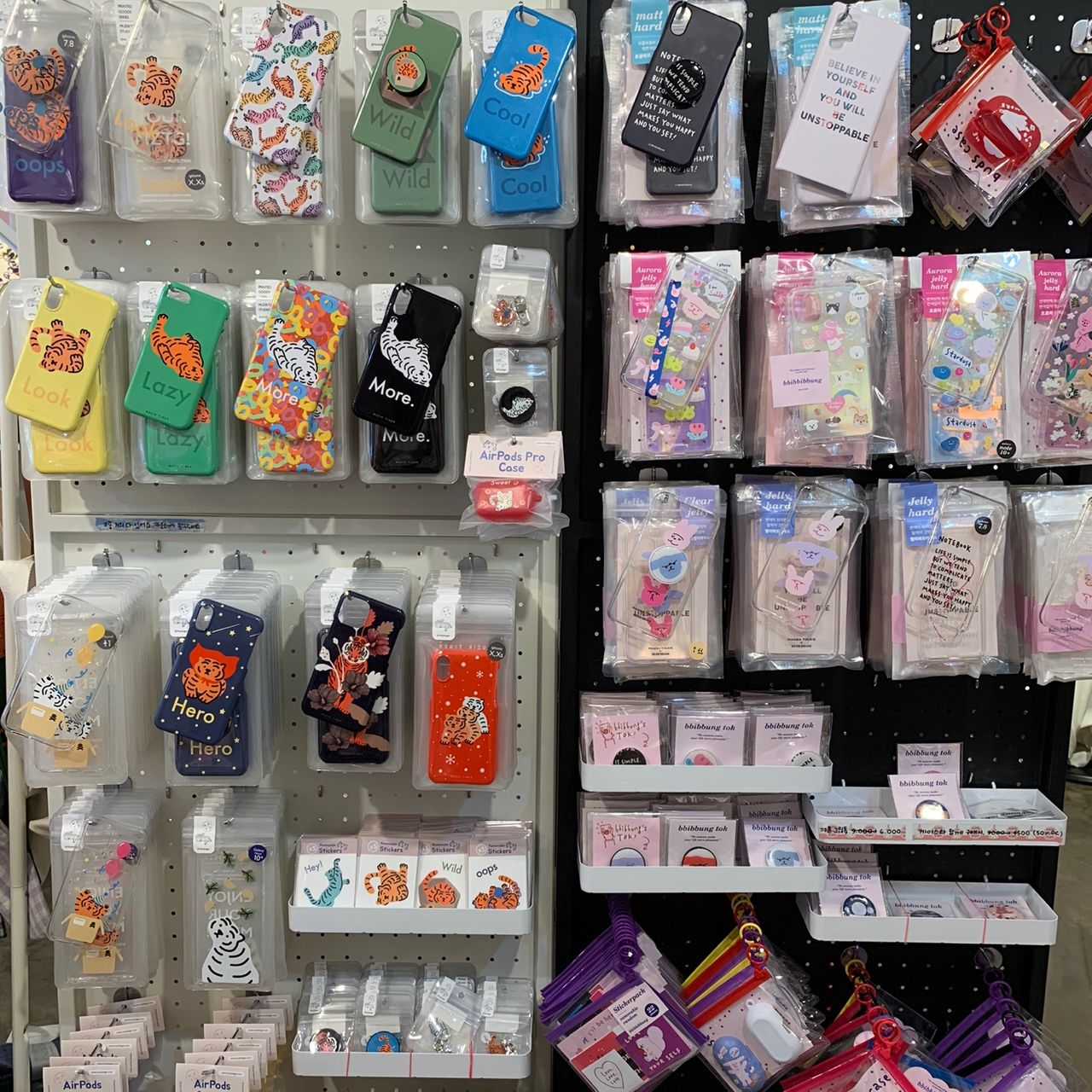 Vari accessori per telefoni e piccoli gadget decorativi esposti su una parete colorata a Hongdae.