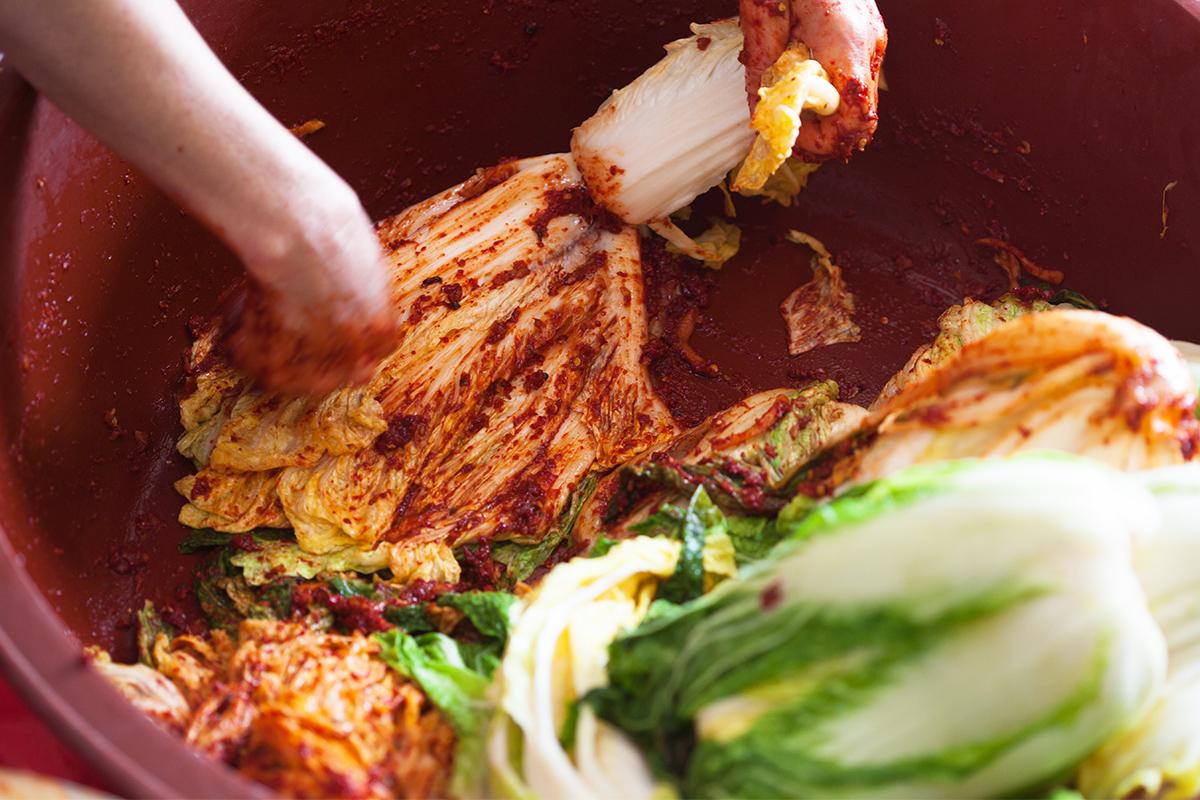 Mixing kimchi ingredients by hand as part of the preparation process at Seoul Kimchi Academy.