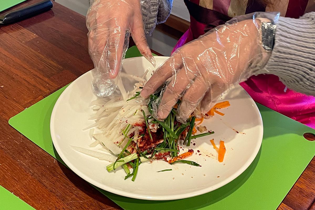 Mixing vegetables and spices by hand in the preparation of authentic Korean kimchi.