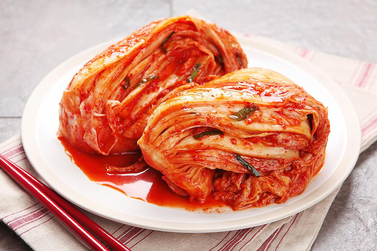 Instructor at Seoul Kimchi Academy wearing traditional Hanbok attire and demonstrating kimchi making.