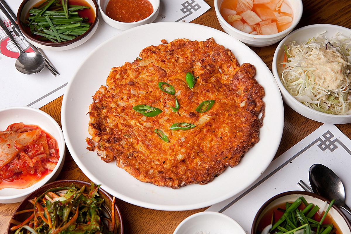 Kimchi being made with vibrant spices, vegetables, and napa cabbage at a cooking session.