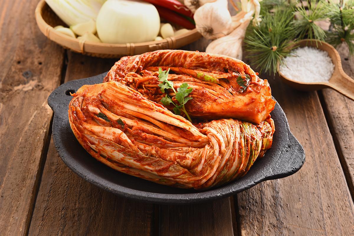 Close-up of freshly prepared cabbage kimchi displayed with various vegetables and ingredients.