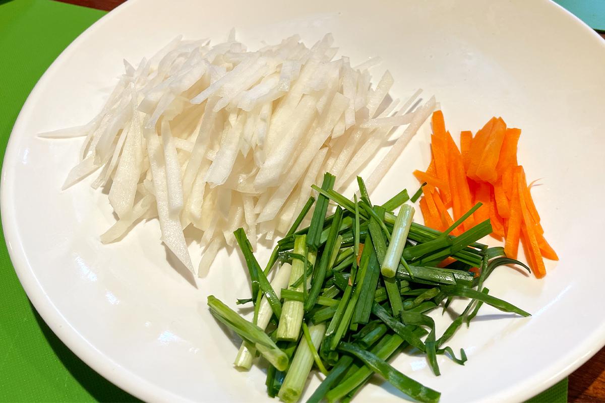 Julienned vegetables ready for mixing with spices during the kimchi-making process.