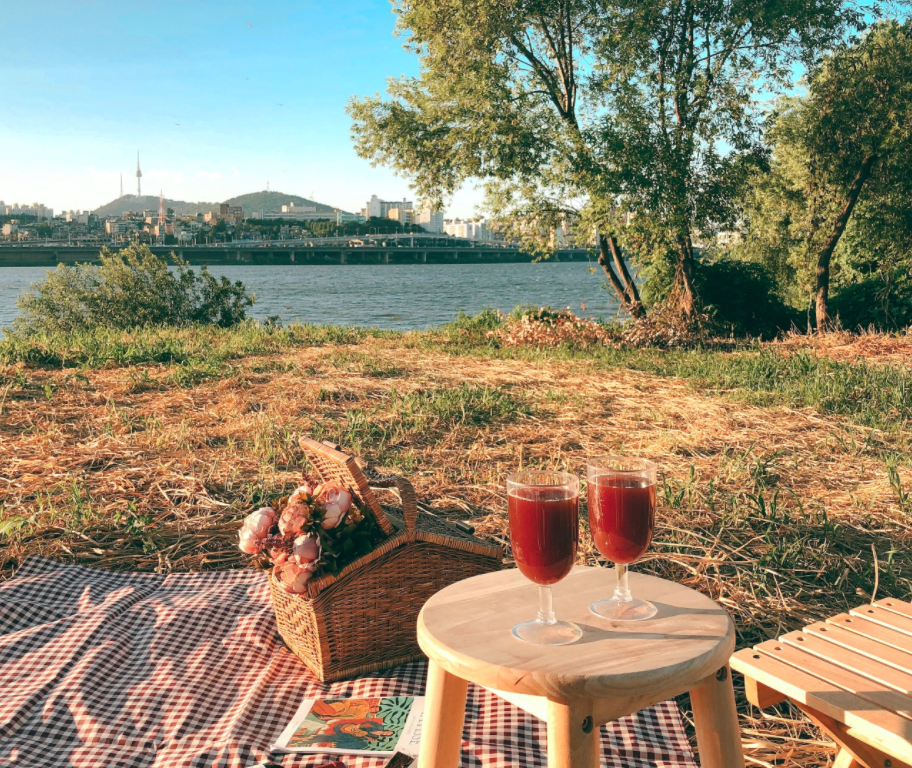 Романтический пикник у реки с видом на Сеул, два бокала вина на фоне реки.