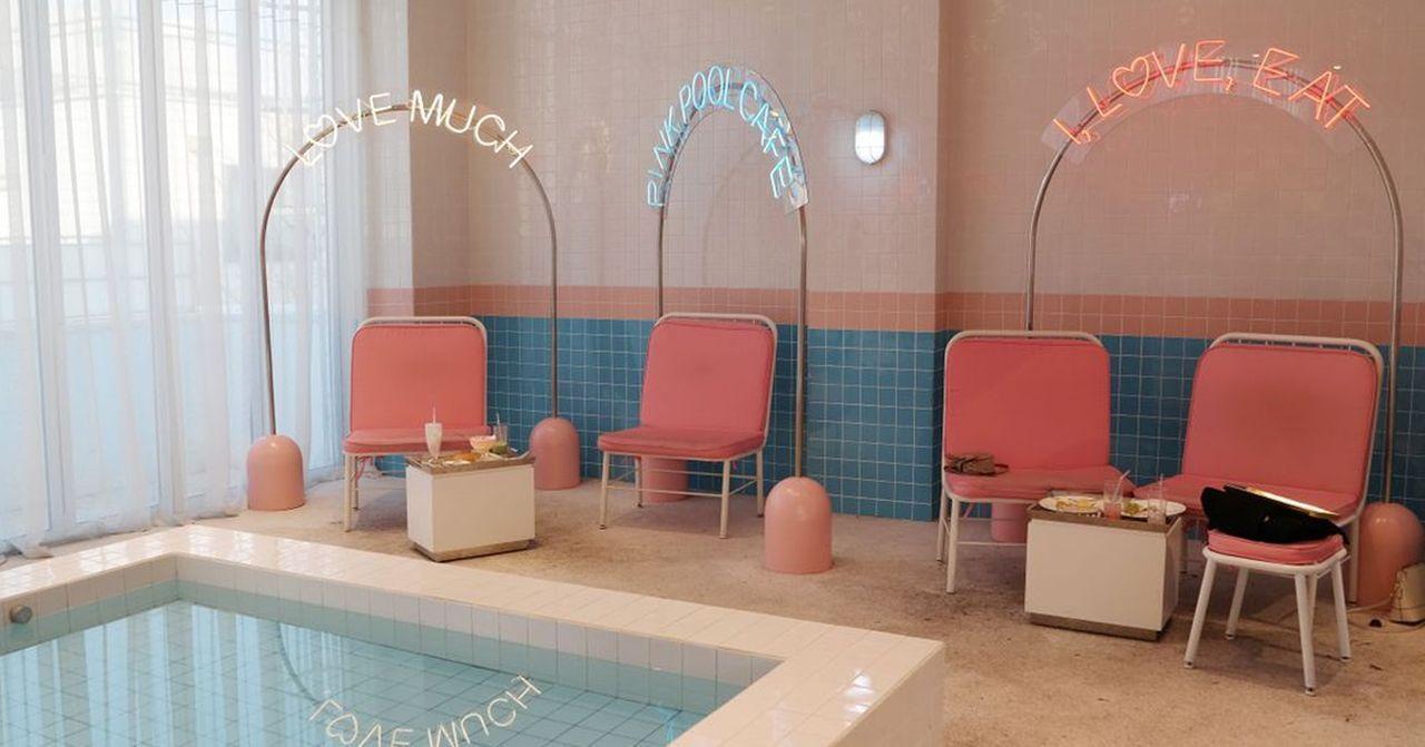 室内泳池派对场地，粉蓝色调设计，配有吊椅和灯饰，适合举办小型活动。