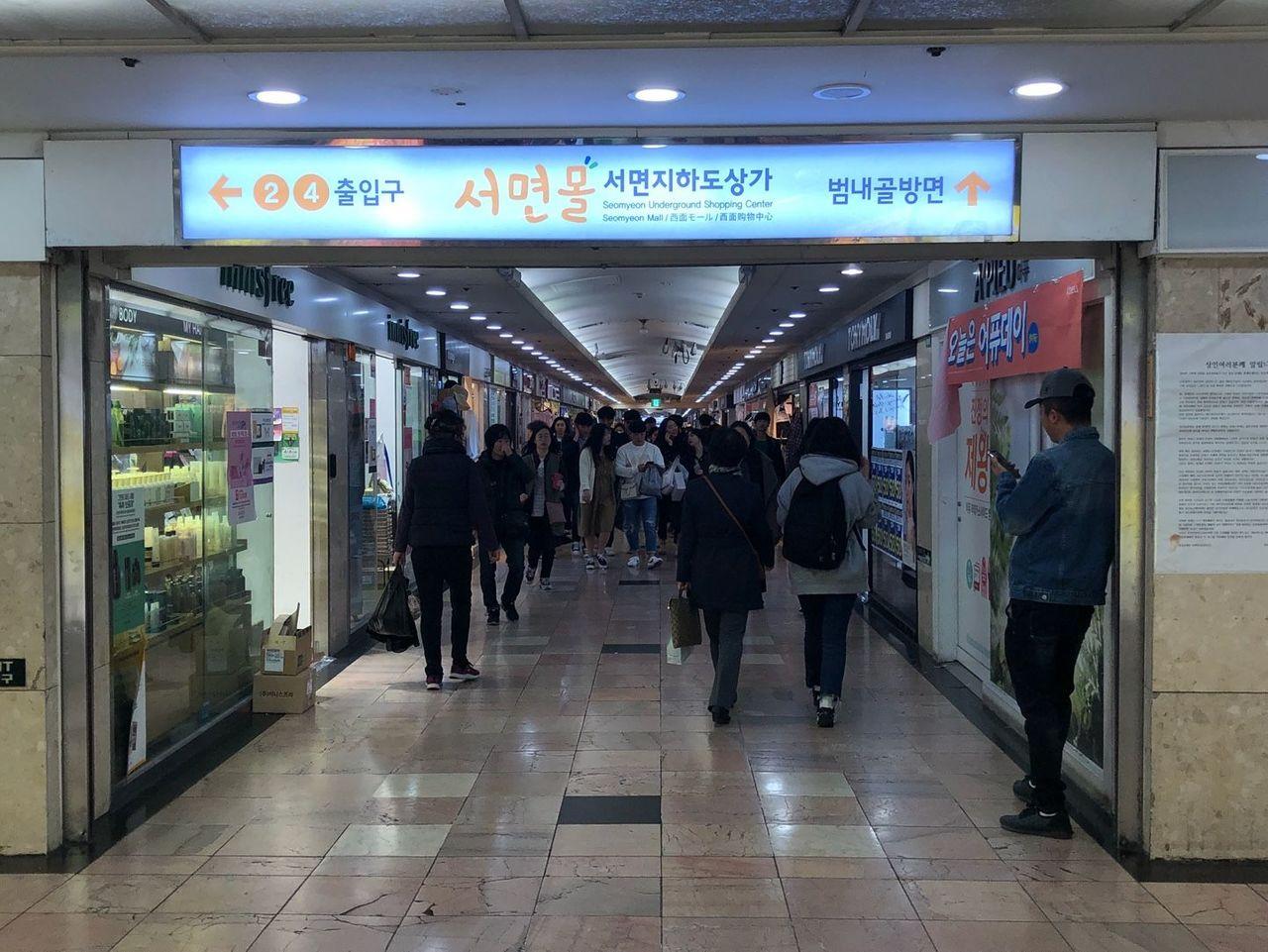 釜山西面地下街内景，韩国时尚服饰店，畅销商品，顾客在购物。