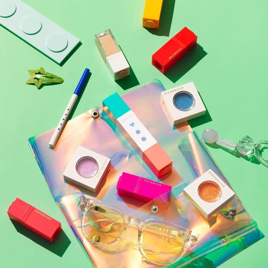 石頭磚多樣小型化妝品，搭配獨特眼鏡配飾於綠色背景上，彰顯創意風格。