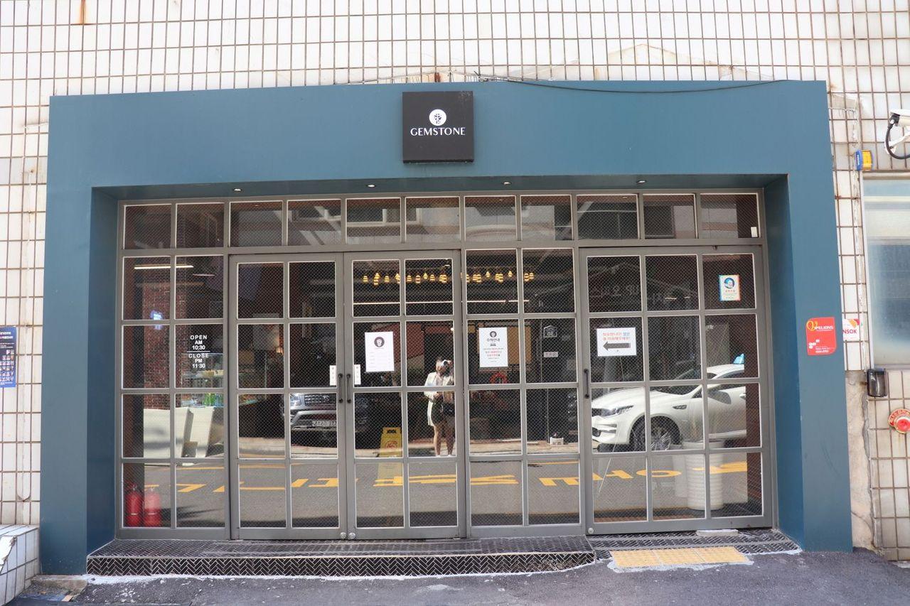 GEMSTONE咖啡廳的正門入口，位於釜山南浦洞附近，展示了乾淨的玻璃門和標誌，上面寫著咖啡廳的營業時間。