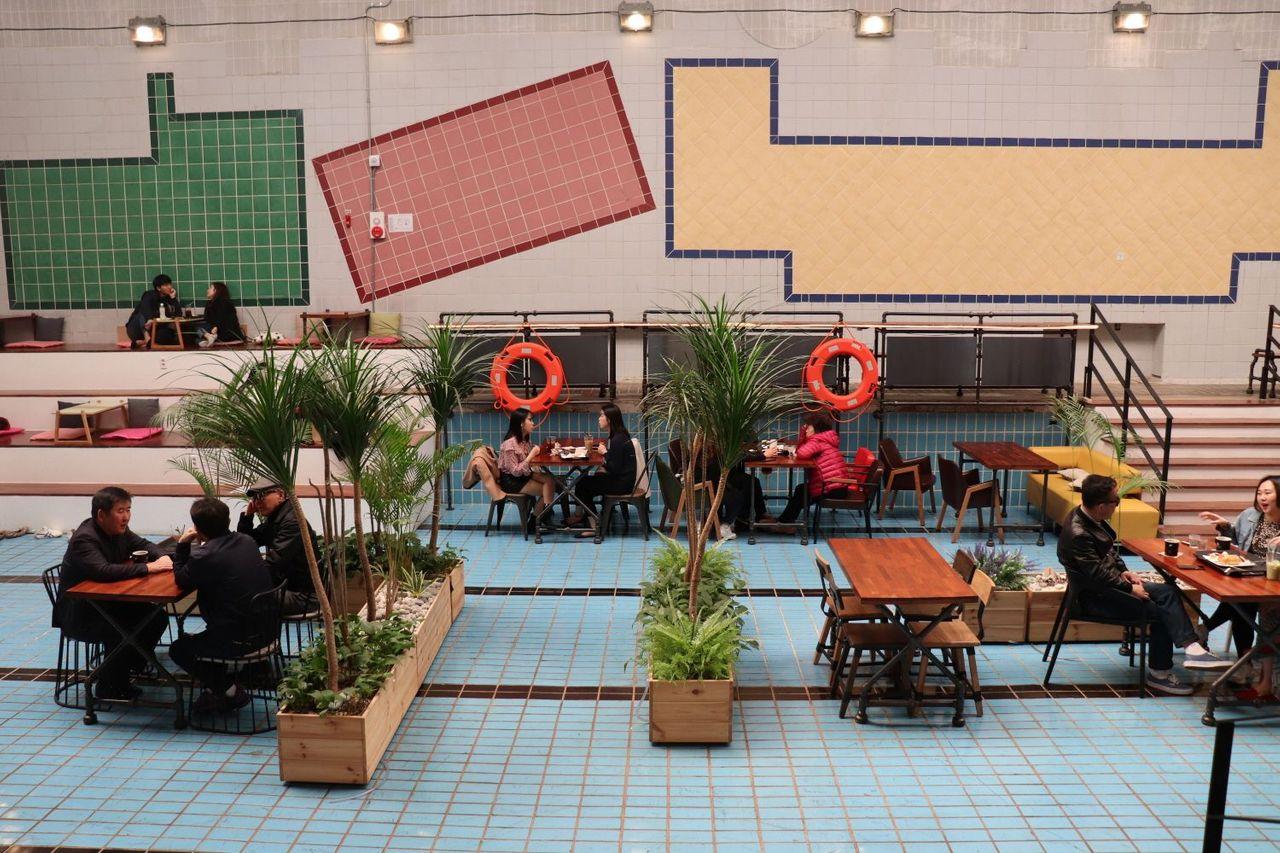 Өнгөрсөн усан бассейны орой дээр, стильтэй тавилга бүхий Cafe Gemstone-ийн зочид сууж буй орчин.