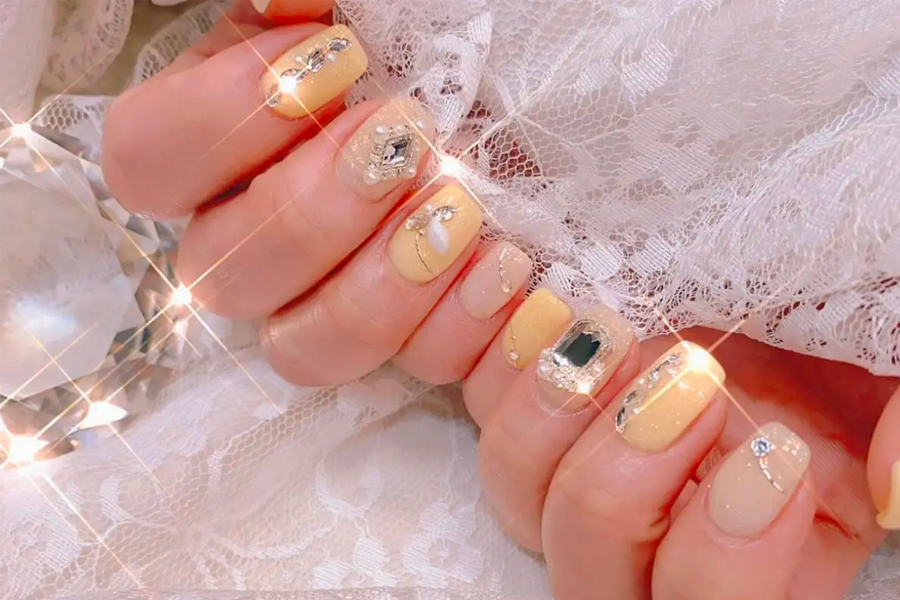 在珠寶與蕾絲襯託下的閃亮黃鑽美甲，展示豪華與吸引人的美甲設計。