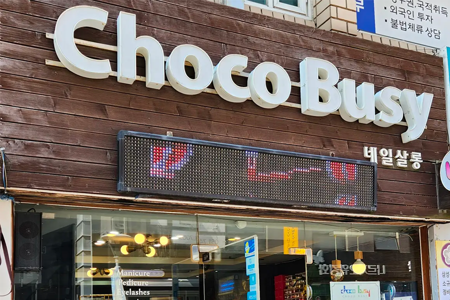 釜山的Chocobusy Nail美甲店的店面外觀，顯示出用木製裝飾的招牌與店門口。