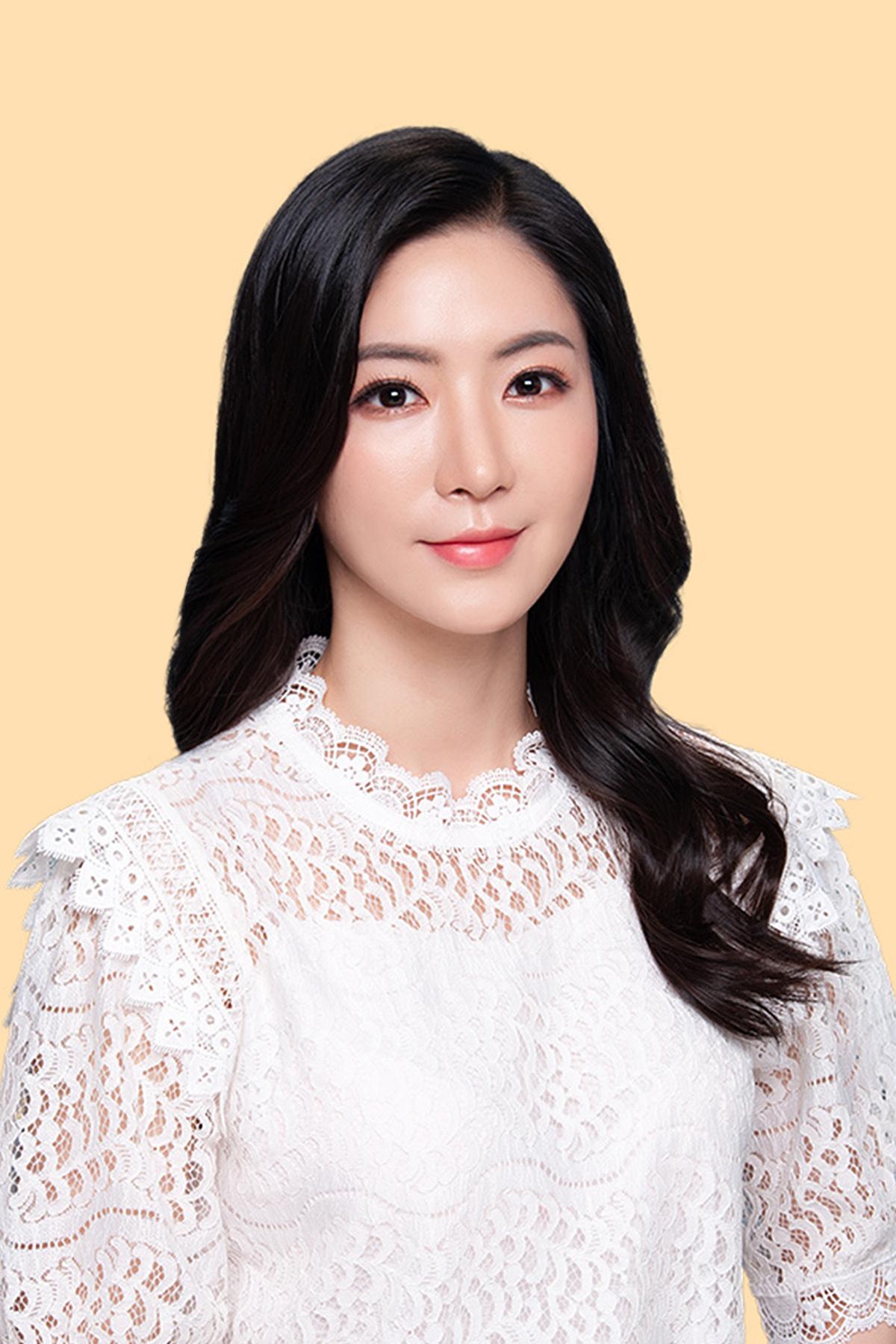 韓国の写真館で撮影された女性、白いレースのトップス、淡いオレンジ色の背景