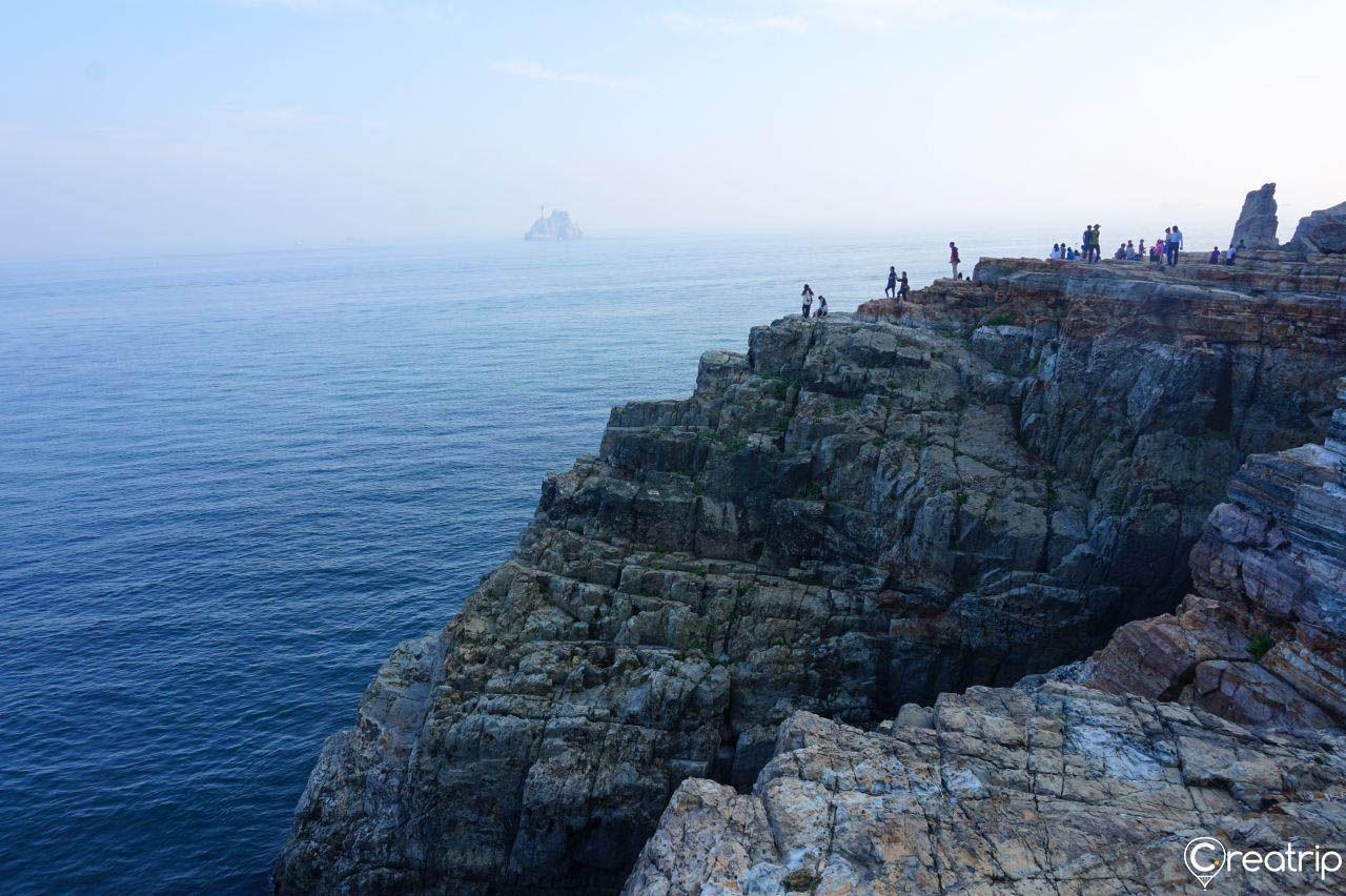 从太宗台眺望海岸线，岩石嶙峋，海水碧蓝，游客在岸边观赏风景。