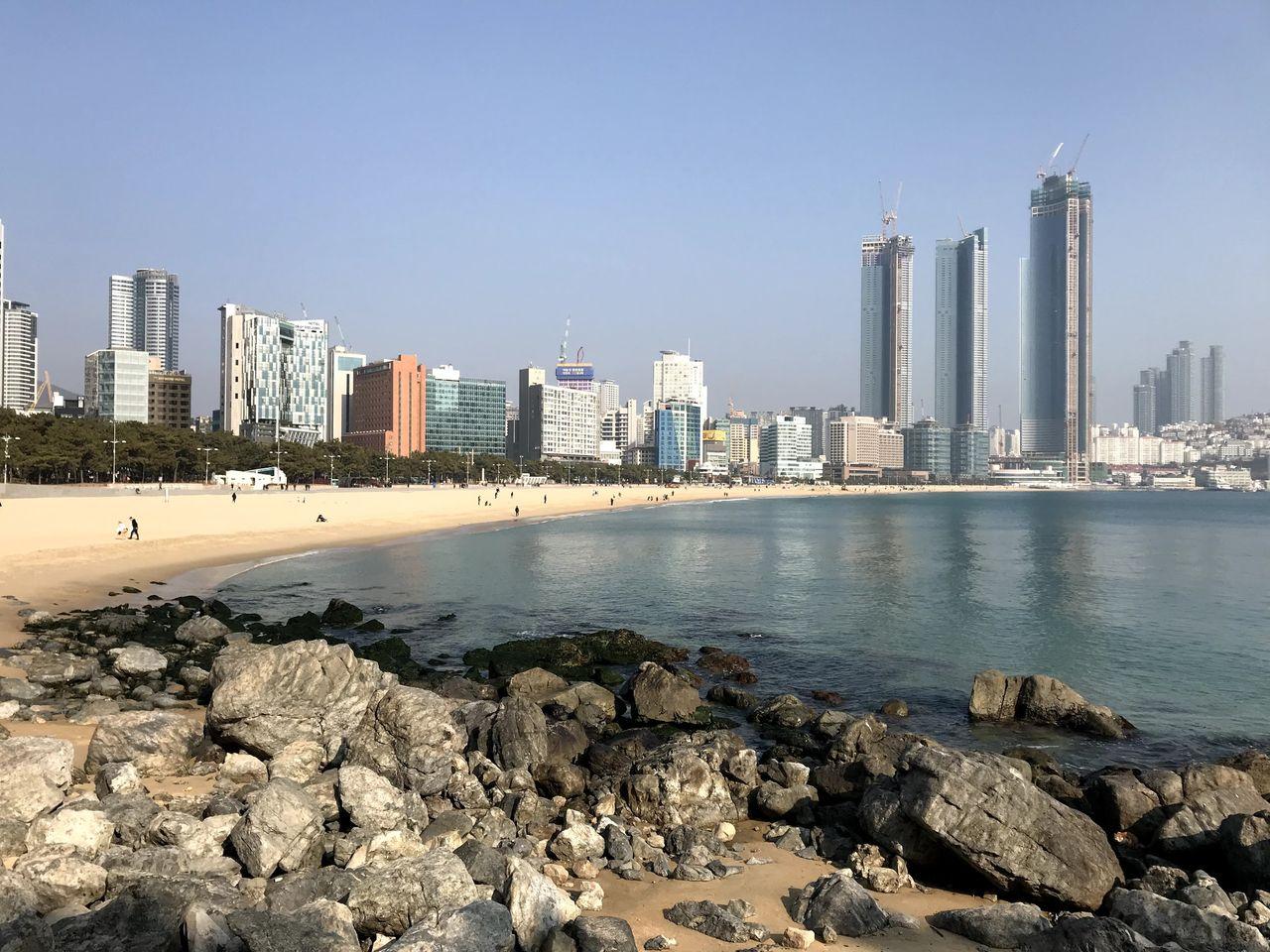 釜山海云台海滩的海岸，全景展示沙滩与现代建筑。