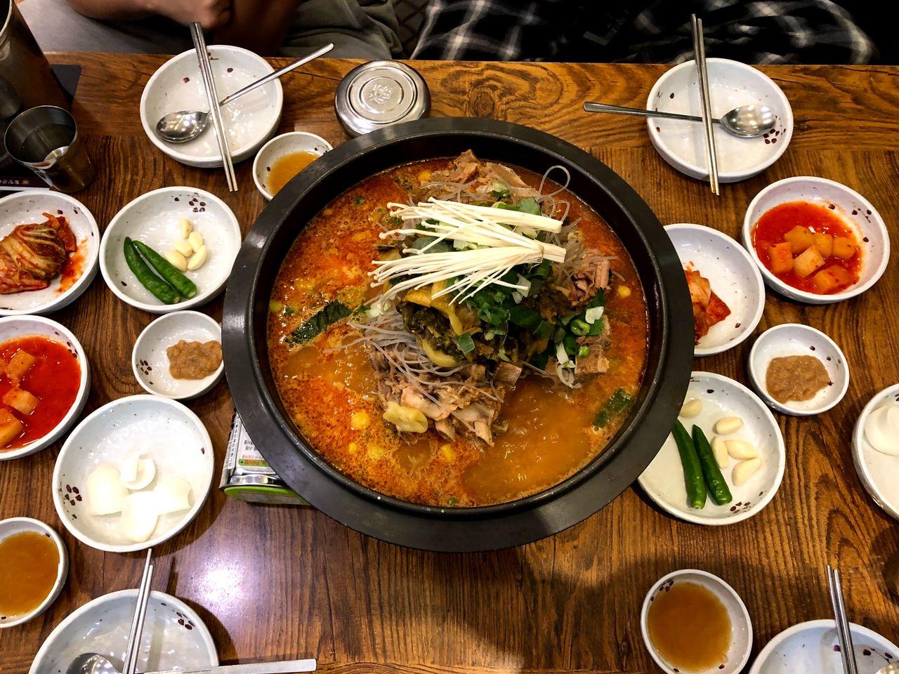 釜山韩式料理餐桌上的大锅汤，周围摆满了小碟冷菜，充满韩国风味。