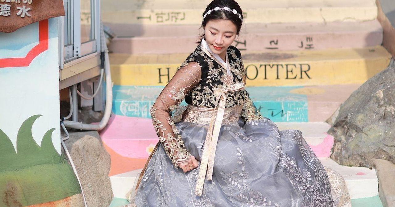 穿着精美韩服的游客坐在釜山著名景点甘川文化村的台阶上。
