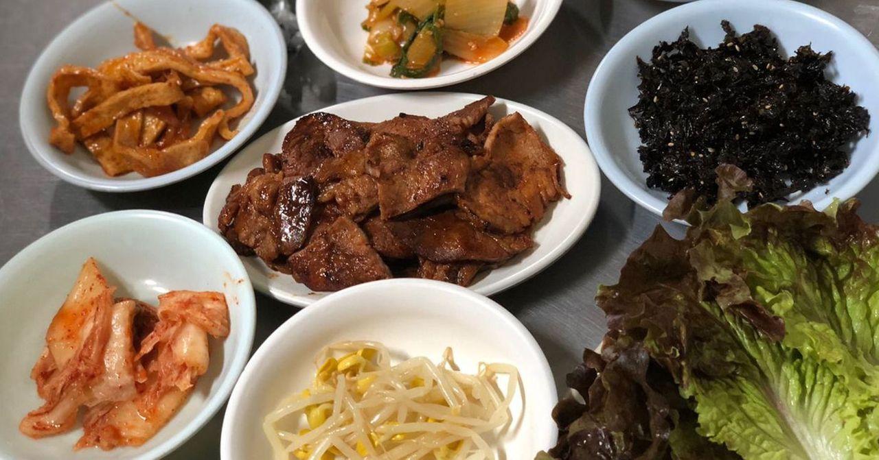 韓國燒肉店的小菜和烤肉，包含泡菜與豆芽，傳統韓食。