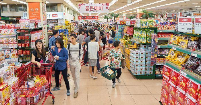 韓國樂天超市內購物情景，琳瑯滿目的零食陳列及人群。