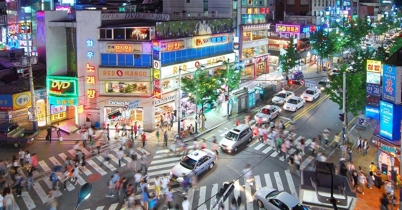 新村地圖懶人包：夜晚的新村街景，五光十色的燈光中，行人匆忙穿梭於熱鬧的街道與商鋪之間。