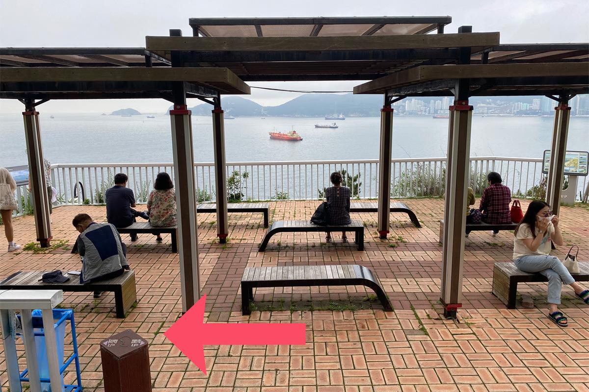 People sitting on benches by the ocean in Huinnyeoul Culture Village