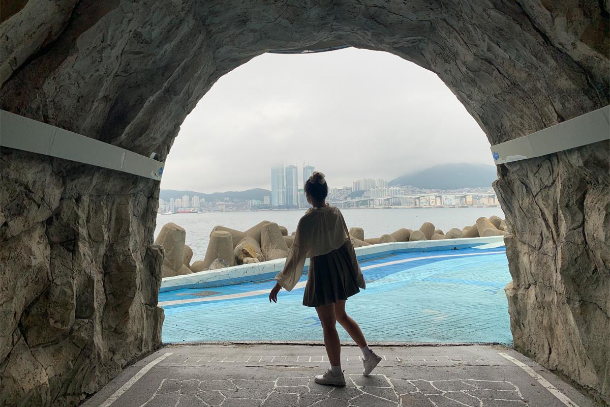 Woman posing at opening of Huinnyeoul Coastal Tunnel with city view