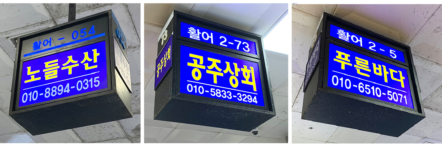 Noryangjin Fish Market partner signs for Nodeul Susan, Gongju Sanghwe, and Purun Bada located within the market, each displaying their respective store numbers and contact details in Seoul.