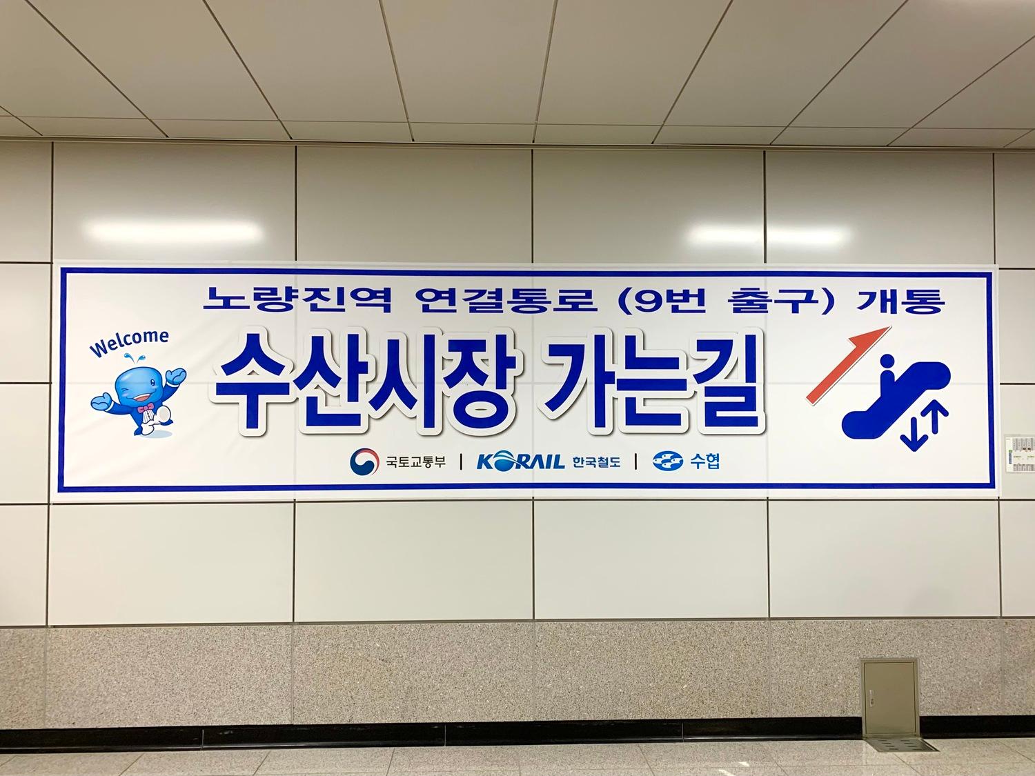 ノリャンジンフィッシュマーケットへの道を示す標識がある地下鉄駅内の写真。韓国ソウルの交通案内情報。