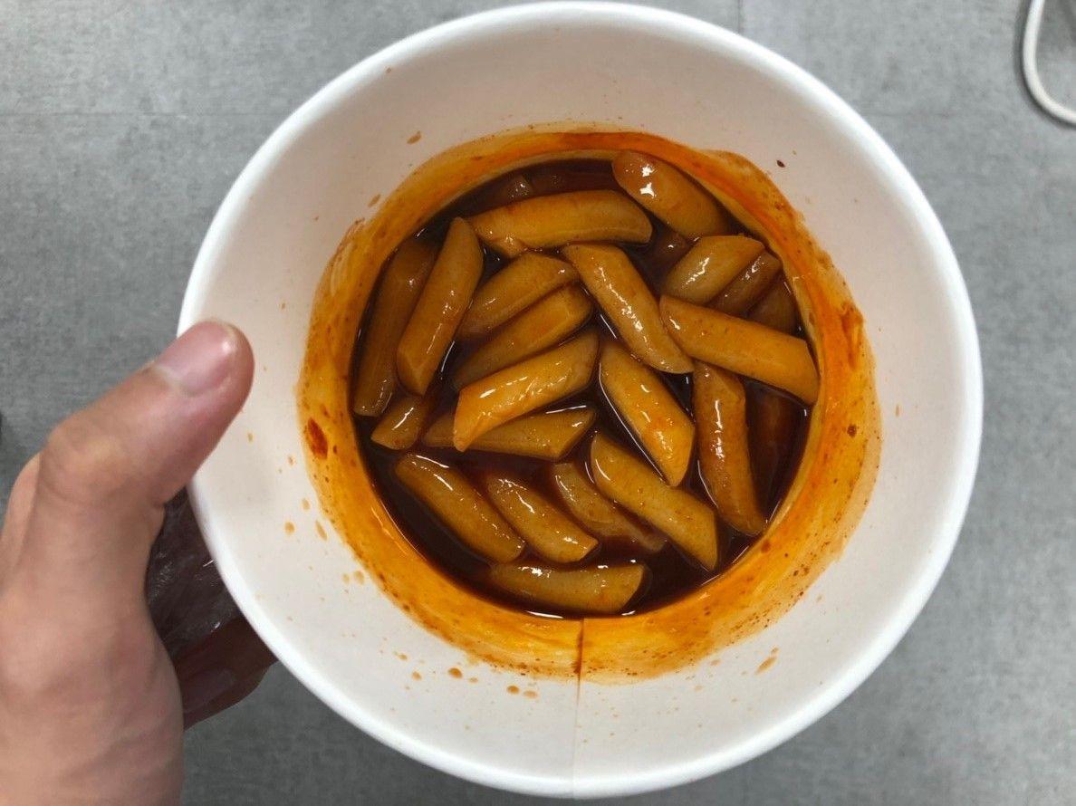 混合后的火鸡辣炒年糕，浓郁的酱汁覆盖着年糕，诱人的辣味美食画面。