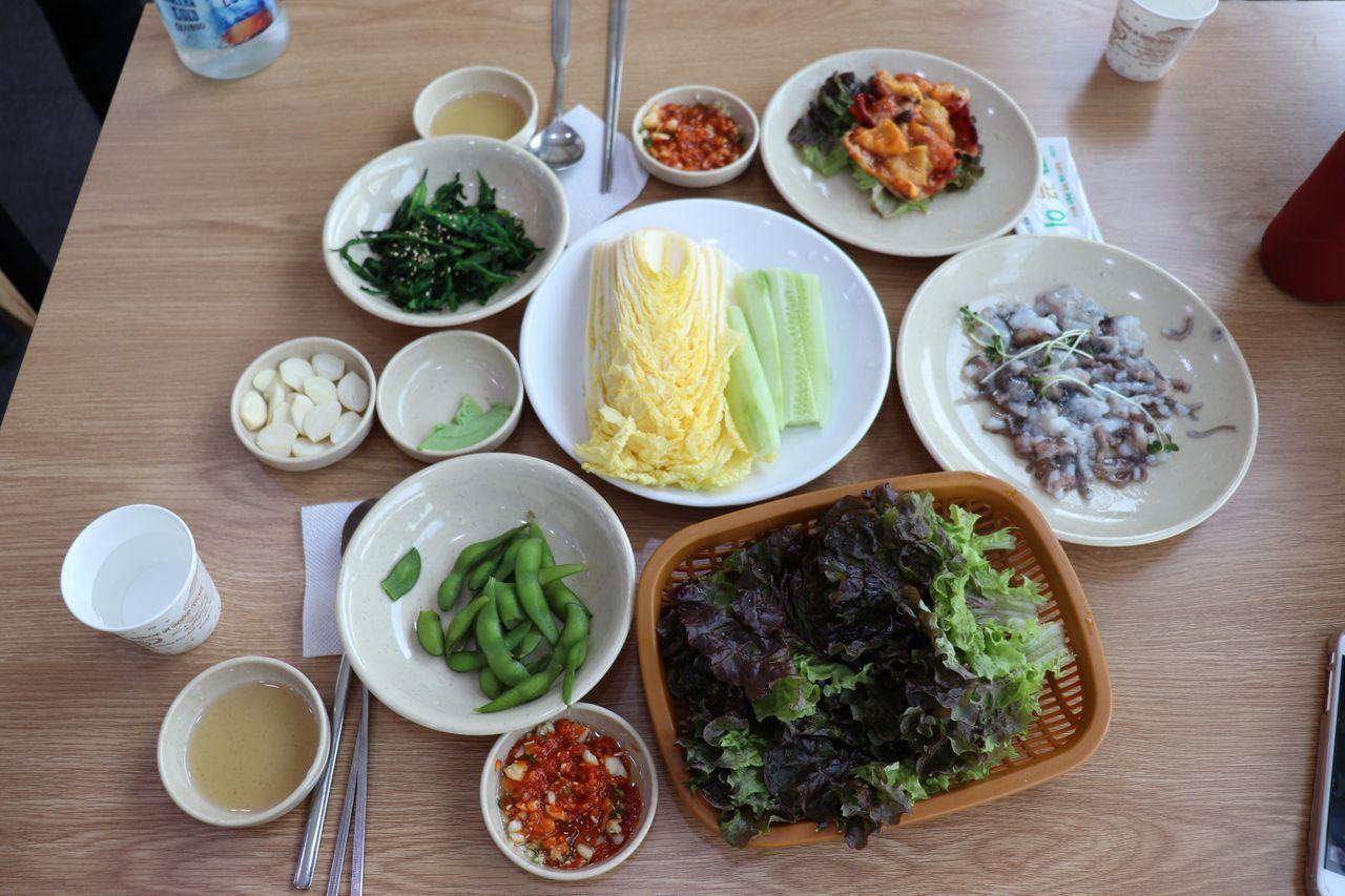 Mesa con platos coreanos, incluyendo diversos acompañamientos y pulpo crudo en el Mercado de Pescado de Noryangjin.