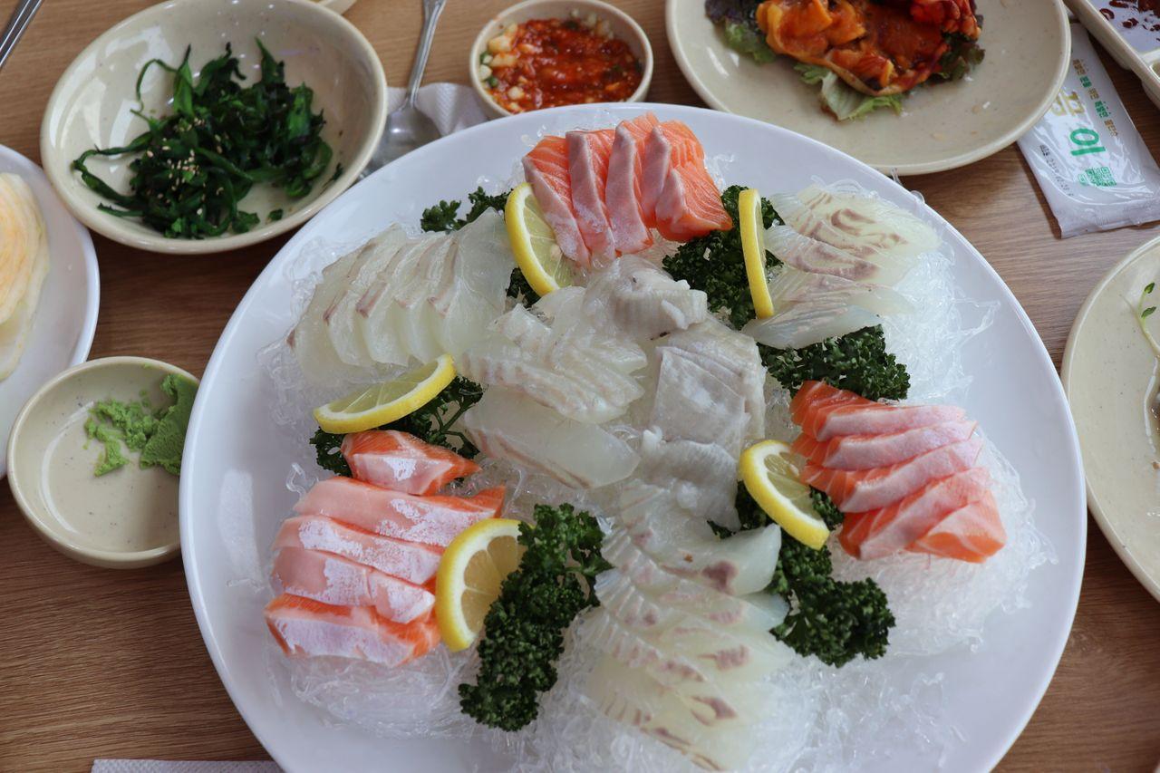 Surtido de sashimi con rodajas de limón y adorno verde, servido en el Mercado de Pescado de Noryangjin.