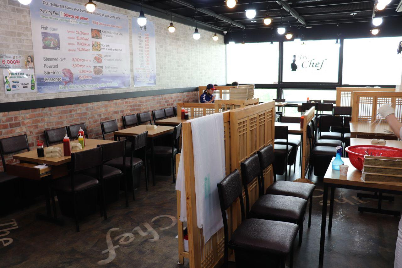 Interior del Millionaire Fish House en el Mercado de Pescado de Noryangjin, mostrado con mesas preparadas para las cenas.